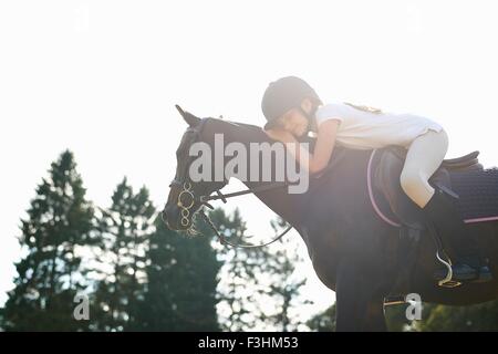 Ragazza a cavallo sporgersi in avanti a cavallo pet Foto Stock