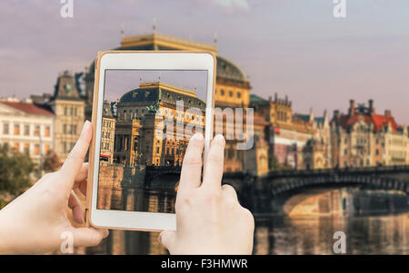 Donna con le mani un tablet. Tenendo shot del famoso storico di Praga vista, il Teatro Nazionale sulle rive del fiume Moldava. Foto Stock