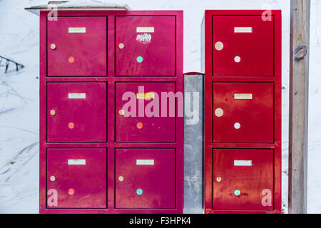 Tre colonne di rosso e di fucsia cassette postali metallico nella neve Foto Stock