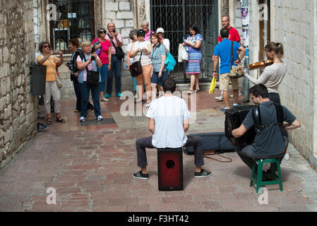 I turisti a scattare foto ad un trio suona per le strade della città vecchia, Kotor, Montenegro Foto Stock