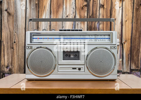 Vintage boombox sulla tavola di legno con capanna rustica parete in legno. Foto Stock