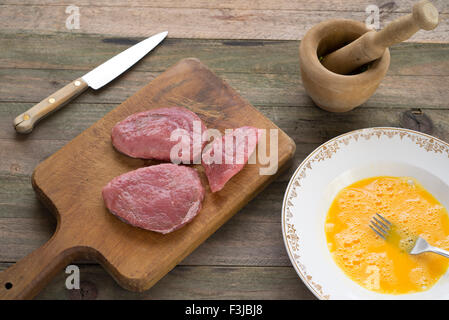 La preparazione di tre porzioni di carne in pastella di uovo Foto Stock