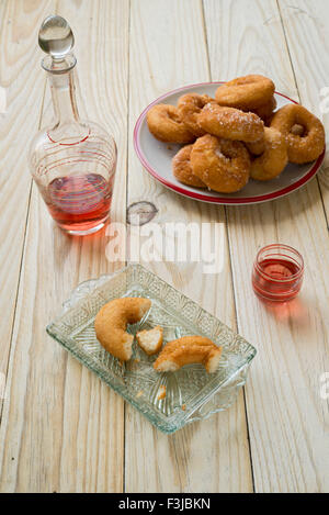 Ciambelle e bottiglia di liquore su un tavolo di legno Foto Stock