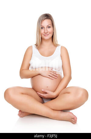 Ritratto di un felice donna incinta seduta sul pavimento e tenendo la pancia Foto Stock