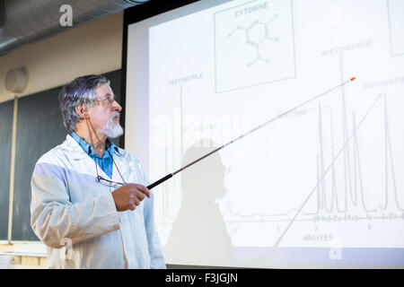 Senior professore di chimica dando una lezione nella parte anteriore dell'aula piena di studenti (SHALLOW DOF; dai toni di colore immagine) Foto Stock