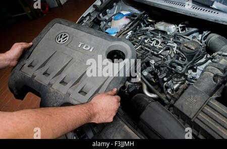 Hannover, Germania. 8 Ott, 2015. Illustrazione - un auto di servizio tecnico tiene il coperchio di copertura di un EA189 2.0 litri TDI motore diesel, che è interessato dalle emissioni di scandalo, in una VW Touran presso un garage ad Hannover, Germania, 8 ottobre 2015. La EA189 del motore diesel software ottimizza la quantità di ossidi di azoto (NOx) risultati durante il test. Foto: JULIAN STRATENSCHULTE/DPA/Alamy Live News Foto Stock