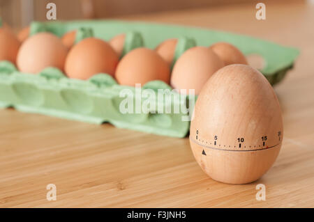 Uovo timer con un cartone di uova fresche in background Foto Stock