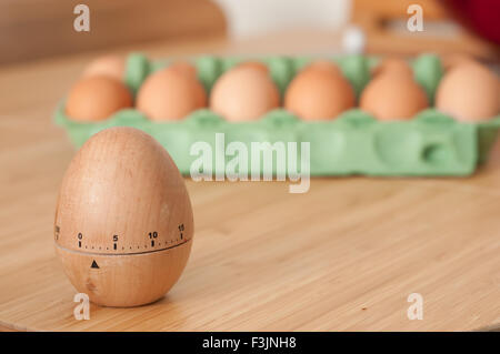 Uovo timer con un cartone di uova fresche in background Foto Stock