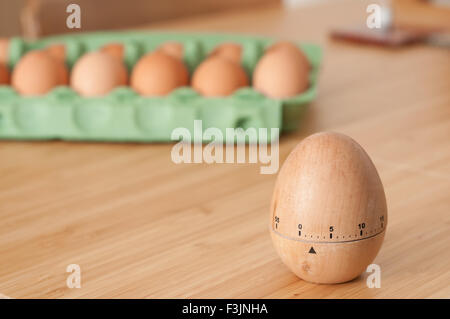 Uovo timer con un cartone di uova fresche in background Foto Stock