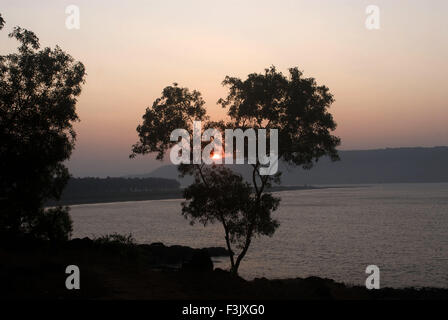 Sunrise dietro di struttura e di montagna con spiaggia rocciosa del mare Arabico ; Harihareshwar Konkan Raigad maharashtra india Foto Stock