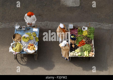 Vista aerea di due handcarts e due venditori uno con vari frutti e altri vegetali con una donna acquirente a Pune India Maharashtra Foto Stock