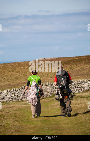 Arrampicatori a piedi con le loro attrezzature per fare un po' di arrampicata su roccia a Devil's scorrere su Lundy Island, Devon, Inghilterra Regno Unito nel mese di agosto Foto Stock