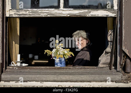 Donna che guarda fuori dalla finestra a casa sua cottage. Black Country Living Museum Dudley West Midlands Inghilterra Regno Unito Foto Stock