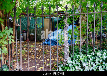 Senzatetto nel Regno Unito che vivono con tenda e teloni semi-permanente nascosti tra gli alberi dietro ringhiere in ferro, Bristol, Inghilterra Foto Stock