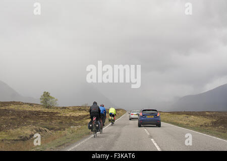 Vetture dando i ciclisti abbondanza di spazio come essi sorpassare sulla A82 strada attraverso Glencoe, Scotland, Regno Unito Foto Stock