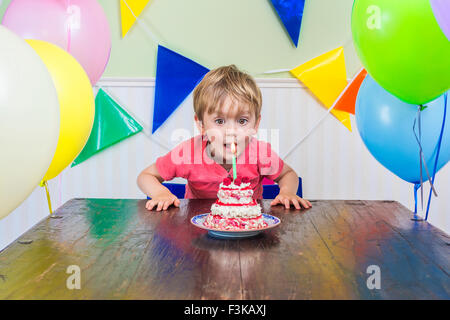 Adorable kid soffiando fuori la candela sulla sua torta di compleanno Foto Stock