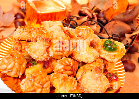 Ingrandimento di una piastra con panellets, alcune castagne arrostite e patate dolci in una cesta e vino dolce in una bottiglia di vetro, typi Foto Stock