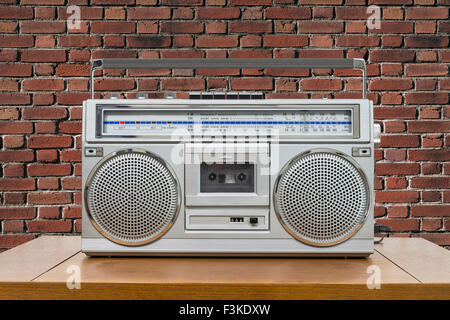 Vintage boombox su tavola in legno rosso con un muro di mattoni. Foto Stock