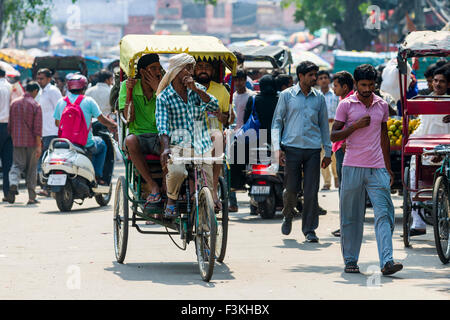 Molte persone e ciclo rikshaws si stanno spostando attraverso le strade del borgo La Vecchia Delhi Foto Stock