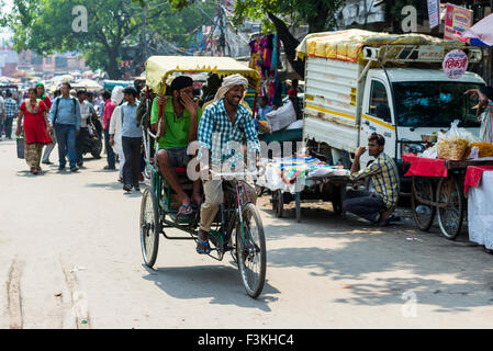 Molte persone e ciclo rikshaws si stanno spostando attraverso le strade del borgo La Vecchia Delhi Foto Stock