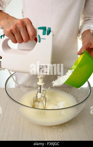 Tenere gli albumi, aggiungere gradualmente lo zucchero semolato. La produzione del cioccolato alle nocciole Torta di meringa Foto Stock