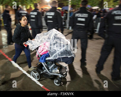 Berlino, Germania. 09oct, 2015. Una donna che spinge la sua PRAM passato gli agenti di polizia che fissano i motivi della carica dello stato di salute e il benessere degli animali (LaGeSo) come rifugiati attendere per la registrazione e l'assegnazione di un posto per dormire nei locali della a Berlino, Germania, 09 ottobre 2015. Foto: Kay Nietfeld/dpa/Alamy Live News Foto Stock