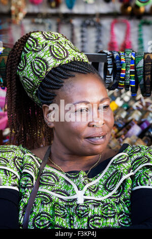 Fornitore di donna con capelli intrecciati, green stampa abito e velo presso la piazza del mercato, Greenpoint, Cape Town, Sud Africa Foto Stock