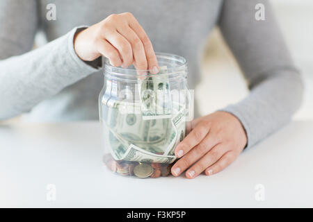 Close up della donna le mani e dollar denaro in vaso Foto Stock