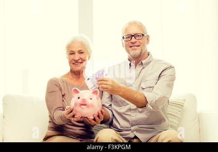 Coppia senior con il denaro e il salvadanaio a casa Foto Stock