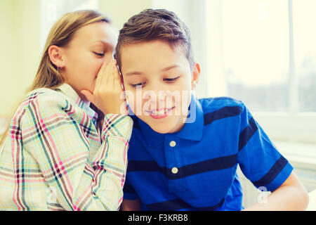 Sorridente schoolgirl whispering a classmate orecchio Foto Stock