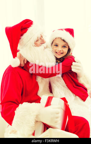 Ragazza sorridente con Babbo Natale e regali a casa Foto Stock