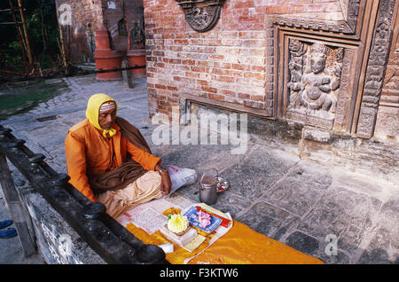 Sacerdote indù leggendo la Sacra Scrittura nella parte anteriore di un tempio ( Nepal) Foto Stock