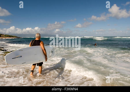 L'uomo Surfer andare all'acqua. Ho'okipa Beach. Maui. Hawaii. Uno dei migliori del mondo windsurf spiagge, Hookipa è anche un favorit Foto Stock