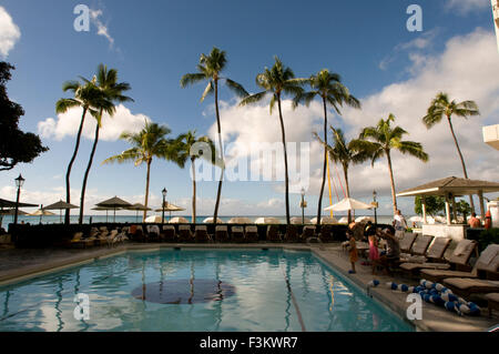 La piscina e il terrazzo al Sheraton Moana Surfrider resort di Waikiki Beach, che si trova sulla spiaggia di Waikiki davanti a Honolulu. Hawaii, Stati Uniti d'America. Hawaii, Oahu, Honolulu, Waikiki, Sheraton Moana Surfrider, banyan tree cortile. Sheraton Moana Surfrider (Hawaii più antica dell'hotel). I vacanzieri godranno di lusso a lato della piscina e la spiaggia di Waikiki. Foto Stock