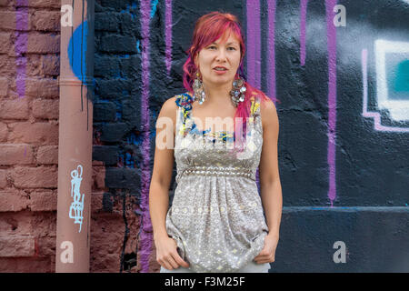 Giovane bella ragazza in harajuku stile con capelli colorati e freaky outfit davanti al muro con la street art pittura Foto Stock