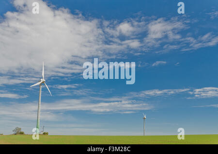 Due impianti di energia eolica in agricoltura paesaggio con cielo blu Foto Stock