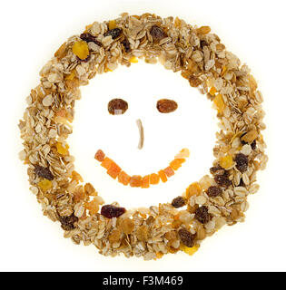 Colazione a base di cereali e muesli conformata in una faccia felice contro uno sfondo bianco Foto Stock