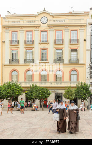 Due monache a piedi attraverso la Plaza de la Constitucion, Malaga, Andalusia, Spagna Foto Stock