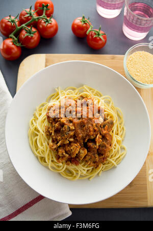 Il ragù alla bolognese realizzato con massa pollo serviti sulla sommità di spaghetti in una ciotola bianco. Vista aerea con ingredienti e cond Foto Stock