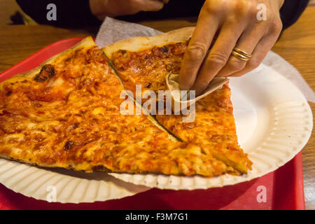 Un consumatore affamato tampona la sua fetta di pizza con un assorbente per assorbire il grasso in eccesso in una pizzeria a New York venerdì 2 ottobre, 2015. Un recente studio rivela che lo sgrassaggio la tua fetta rimuove fino a 76 calorie e 4 1/2 grammi di grasso, o fino a due libbre sul girovita ogni anno. L'americano medio mangia 23 libbre di pizza una volta l'anno. (© Richard B. Levine) Foto Stock