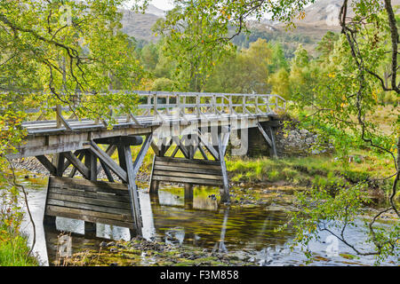 Ponte in legno sul fiume unendo LOCHS CLAIR E COULIN a inizio autunno GLEN TORRIDON Highlands della Scozia Foto Stock