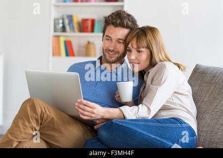 Coppia giovane navigare su internet con il computer portatile. Moderno appartamento bianco in background Foto Stock