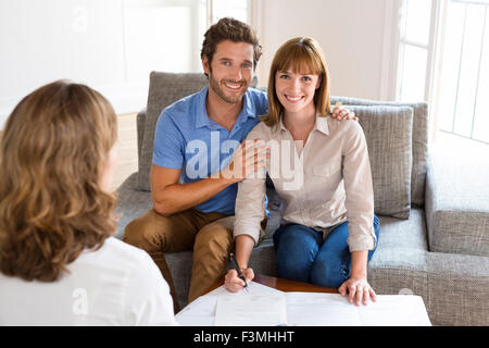 Coppia giovane proprietari incontro agente immobiliare per la casa degli investimenti. La firma di un contratto. Faccia la fotocamera Foto Stock