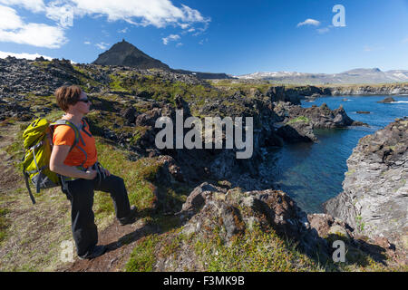 Escursionista sul Hellnar-Arnarstapi sentiero costiero, Snaefellsnes Peninsula, Vesturland, Islanda. Foto Stock