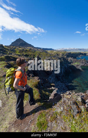 Escursionista sul Hellnar-Arnarstapi sentiero costiero, Snaefellsnes Peninsula, Vesturland, Islanda. Foto Stock