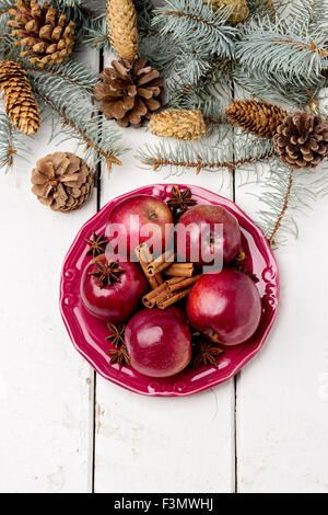 Natale mele e spezie su un tavolo di legno con rami di abete e coni. Messa a fuoco selettiva. Foto Stock