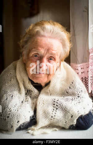 Ritratto di nonna. Una donna anziana seduta al tavolo. Foto Stock
