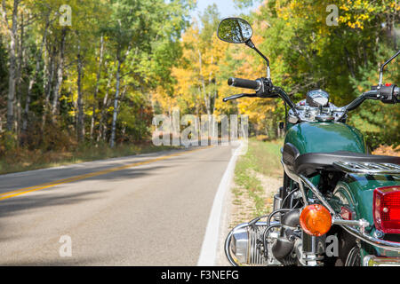 Un motociclo verde accanto a un incurvamento strada aperta in autunno. Il fuoco selettivo sulla motocicletta con spazio copia nella cornice a sinistra. Foto Stock