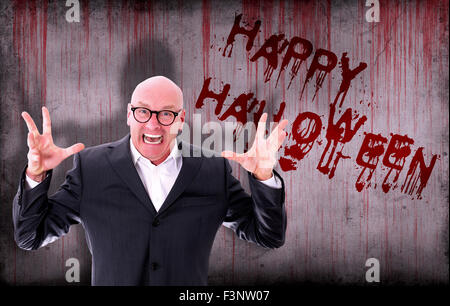 Happy halloween spruzzata su una sanguinosa parete accanto a un imprenditore urlante Foto Stock