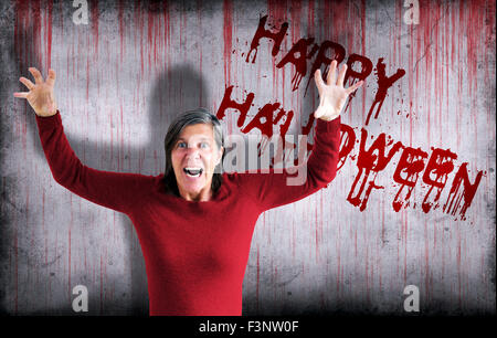 Happy halloween spruzzata su una sanguinosa parete accanto a una donna urlare con denti vampiro Foto Stock